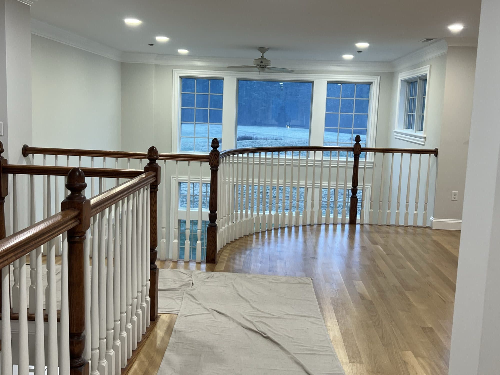 Second-floor landing with white balusters over a polished marble entry