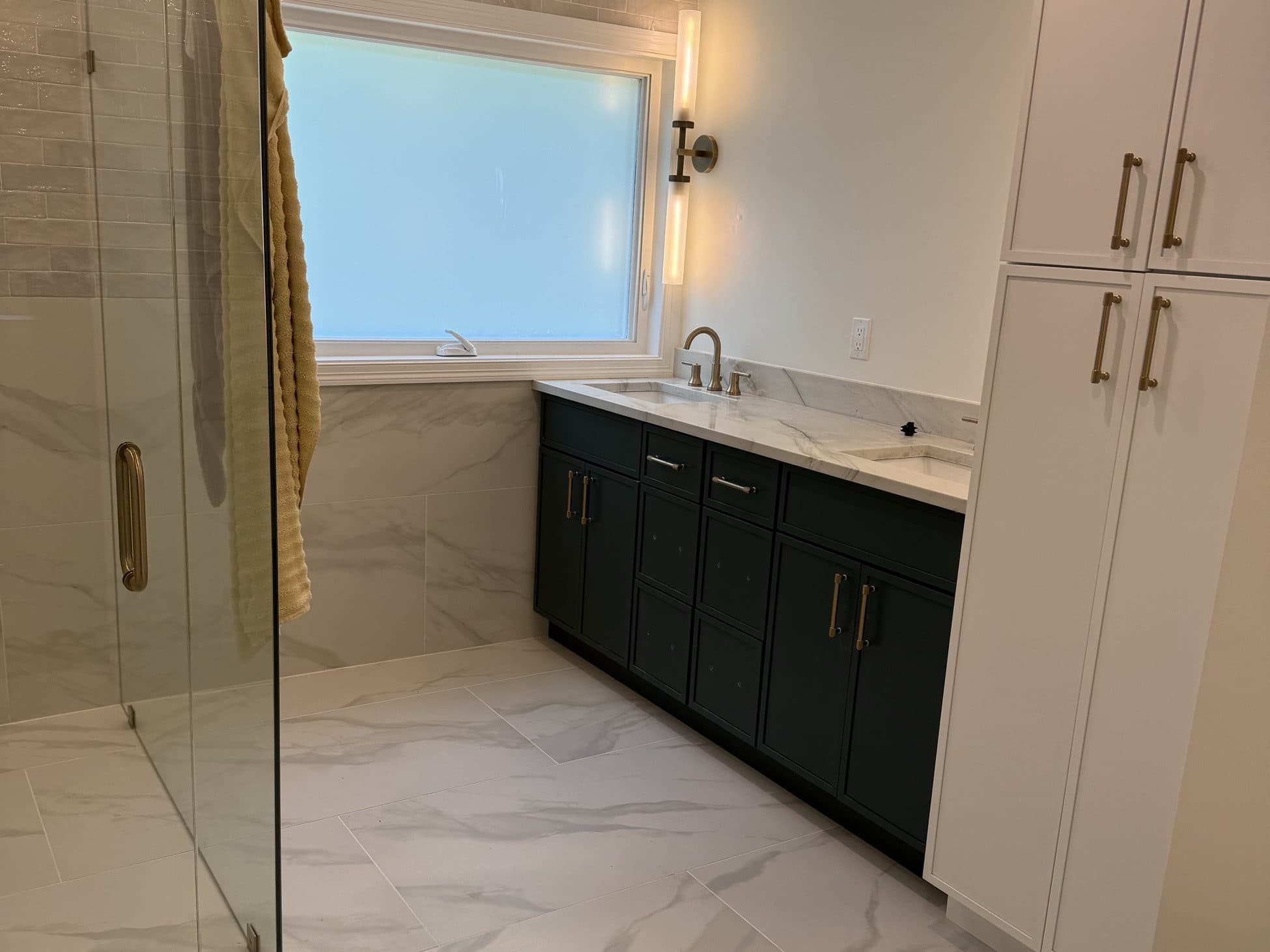 Bathroom with a frameless glass shower, dark vanity and marble tile
