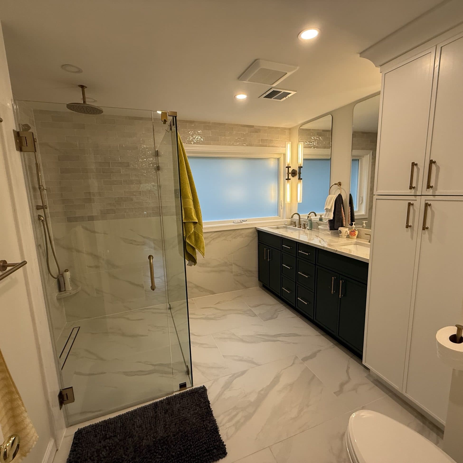 Marble bathroom with a glass shower and a deep navy vanity