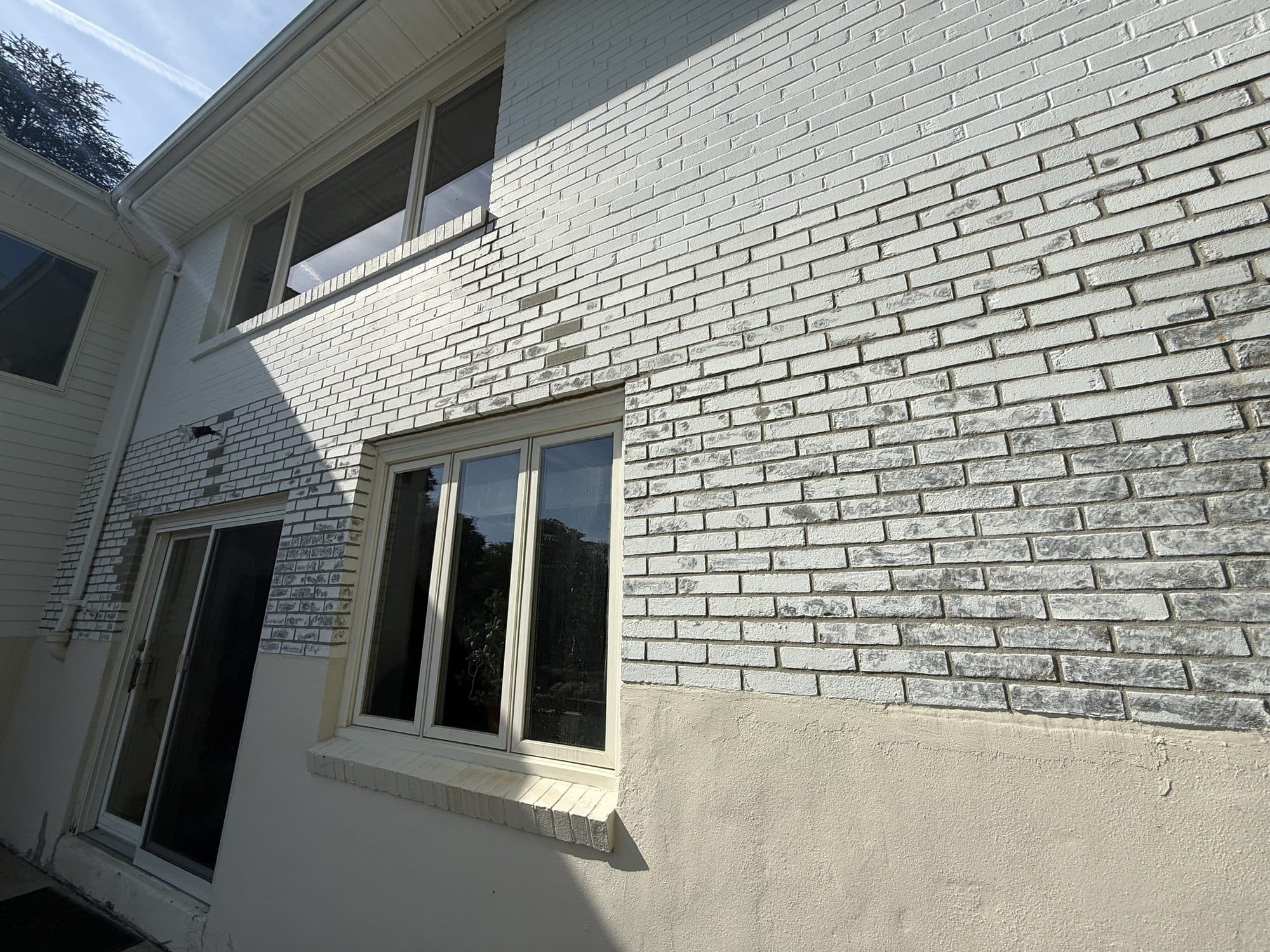 Painted white brick exterior with black window frames
