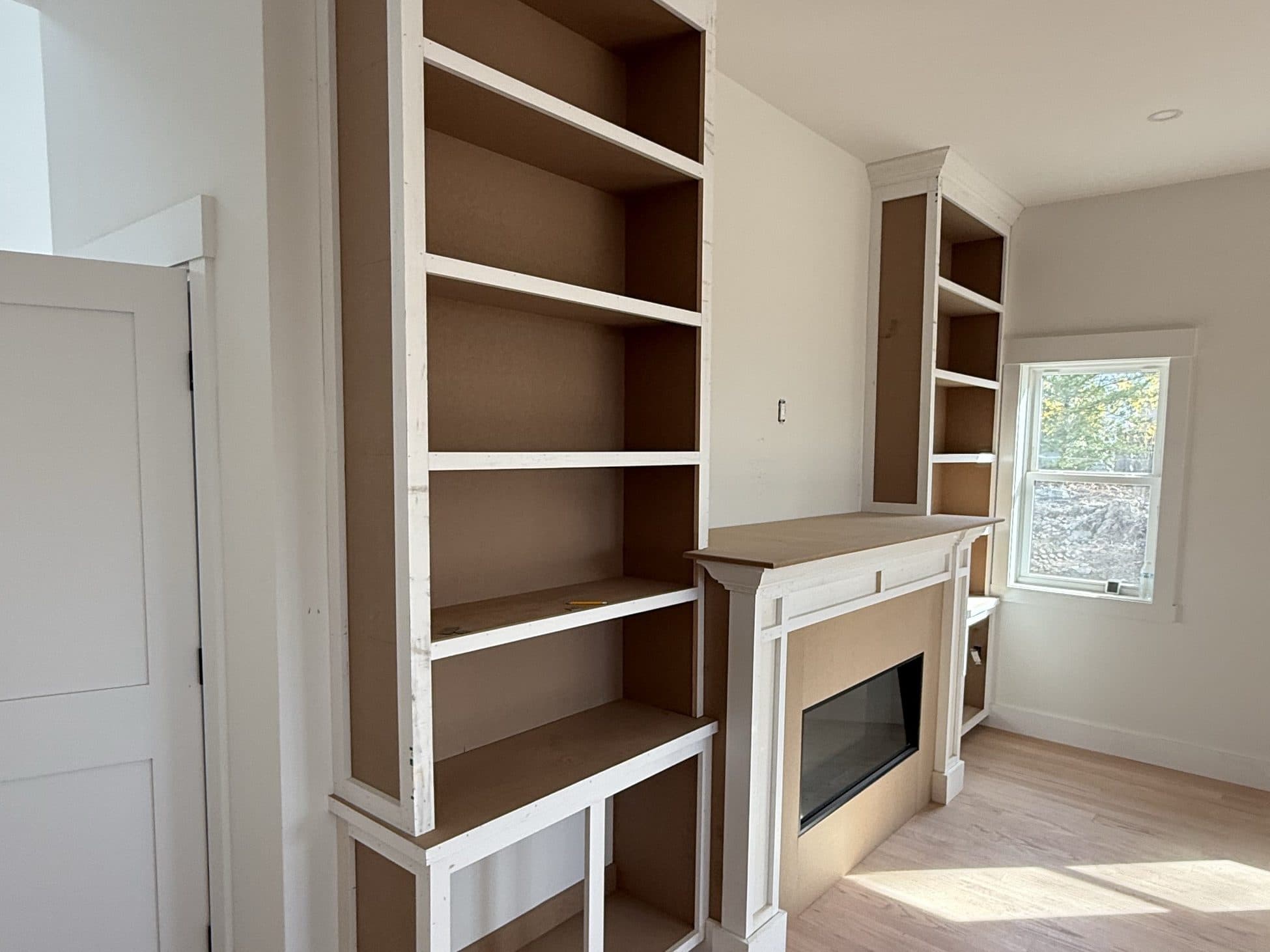 Built-in shelving with wood interiors flanking a fireplace