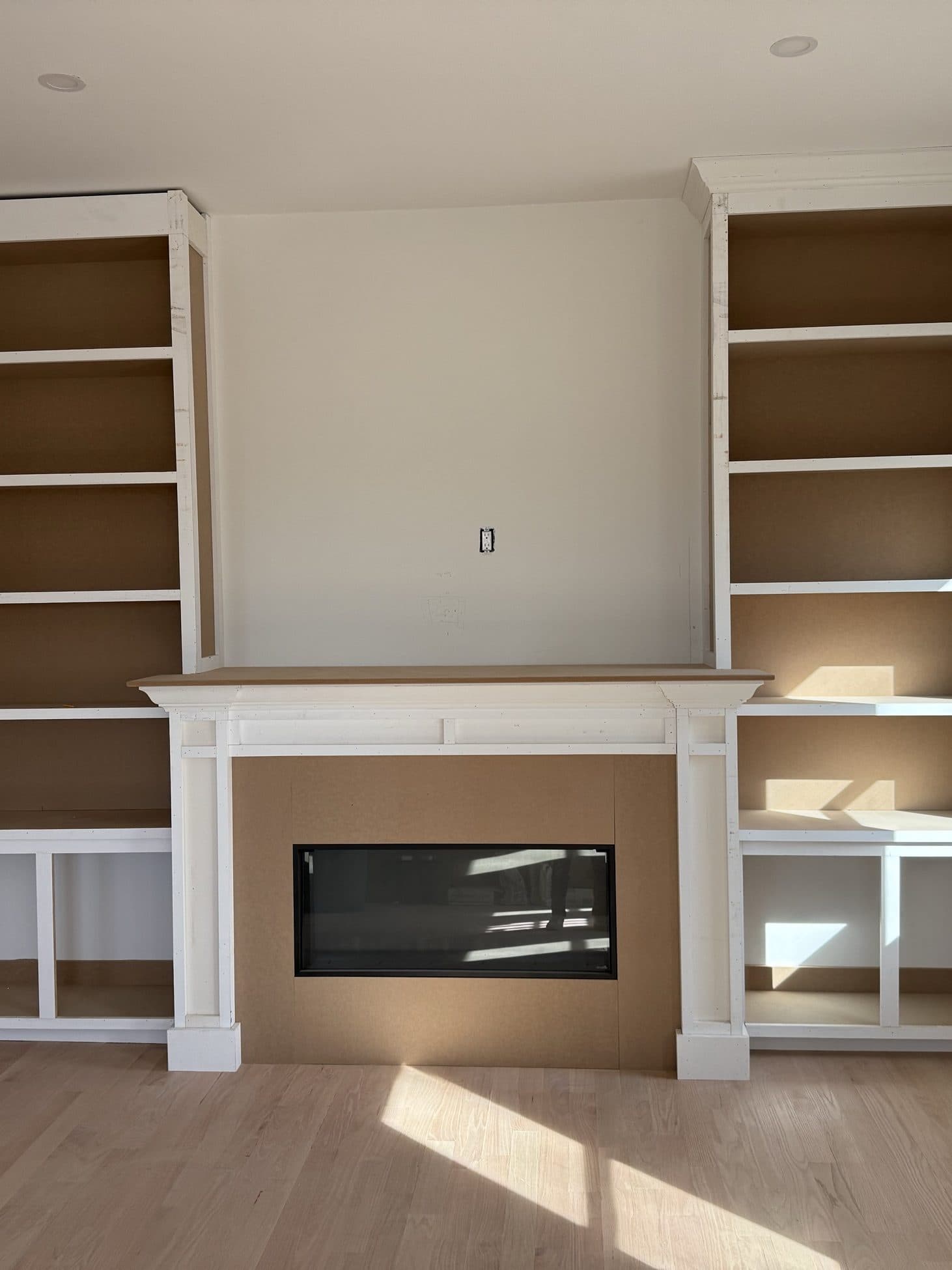 Custom white built-in shelving flanking a modern fireplace