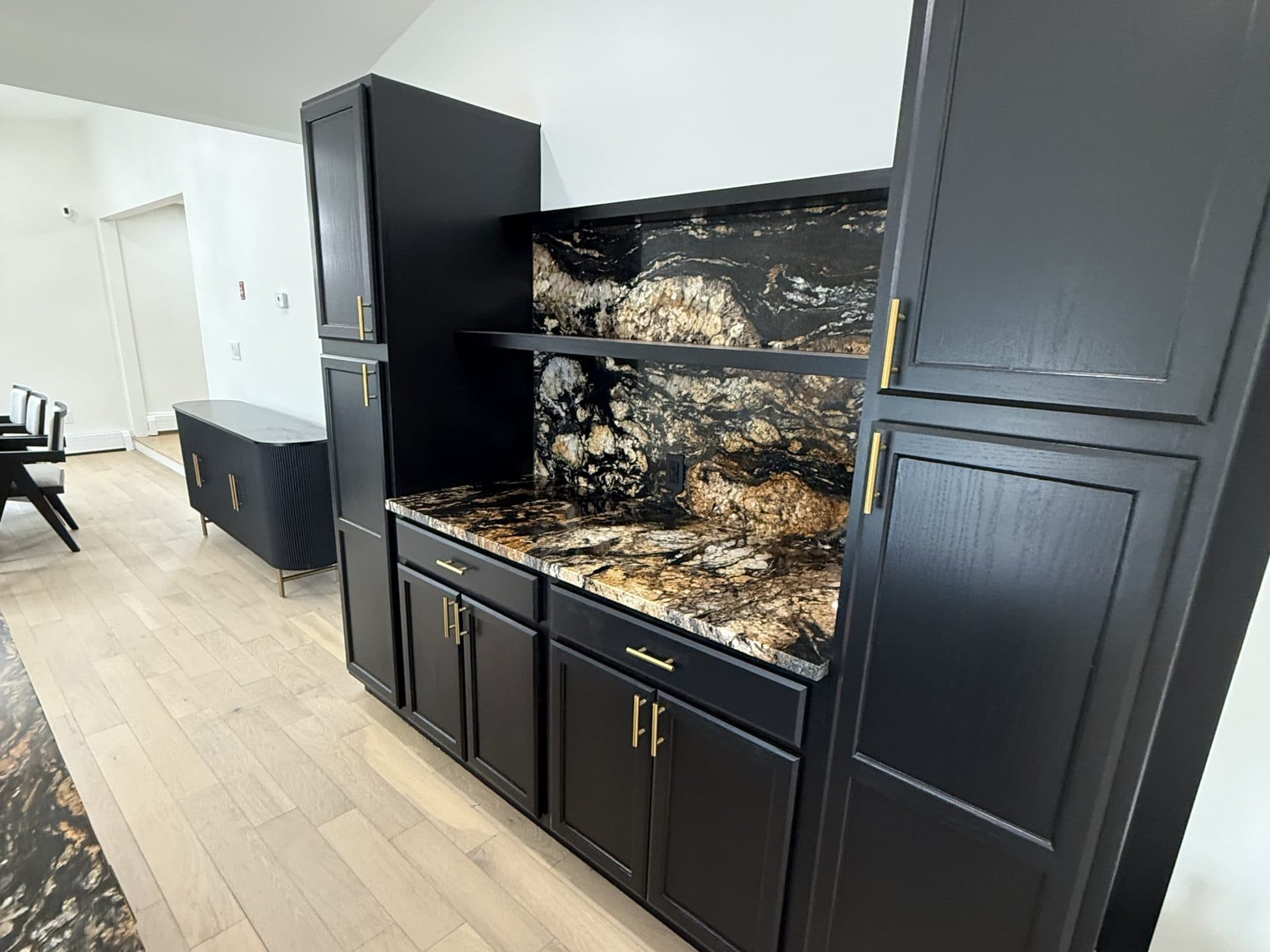 Black kitchen cabinetry with a dramatic granite backsplash