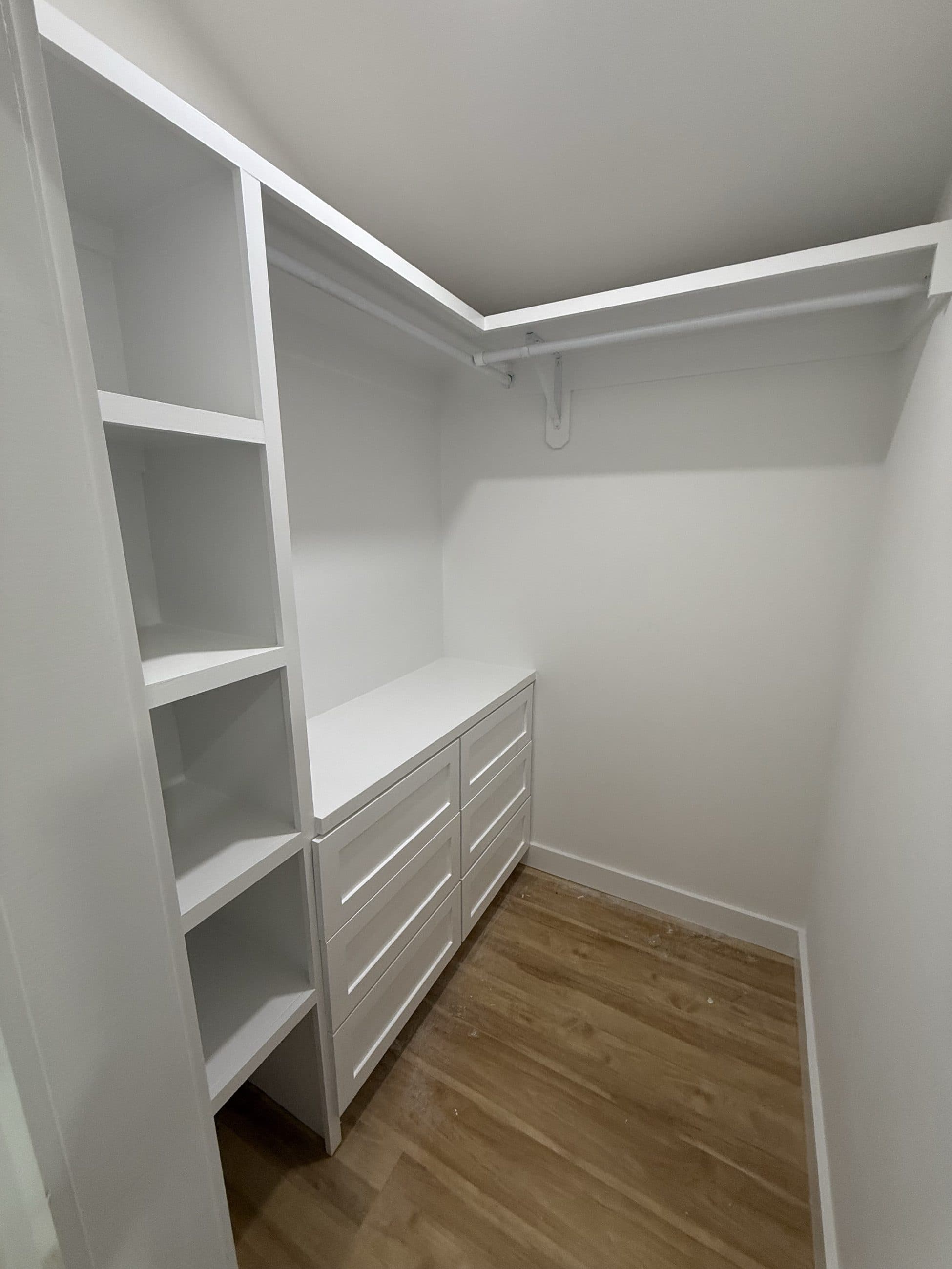 Corner closet with white shelving and drawers