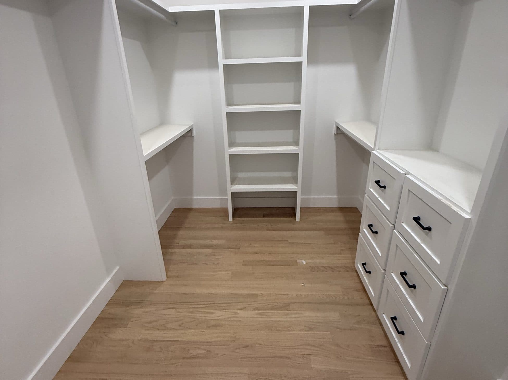 Walk-in closet with white shelving and a built-in dresser