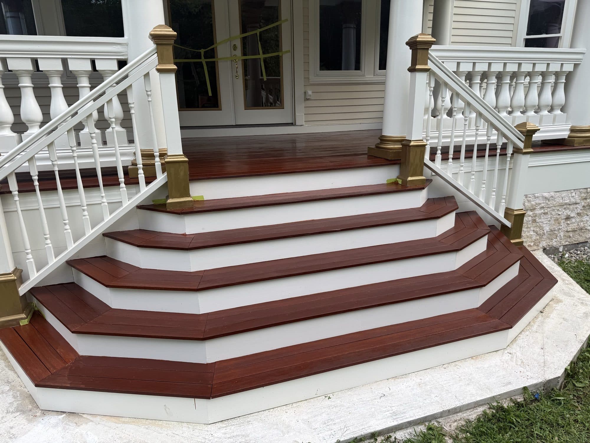 Stained porch steps with crisp white railings and columns