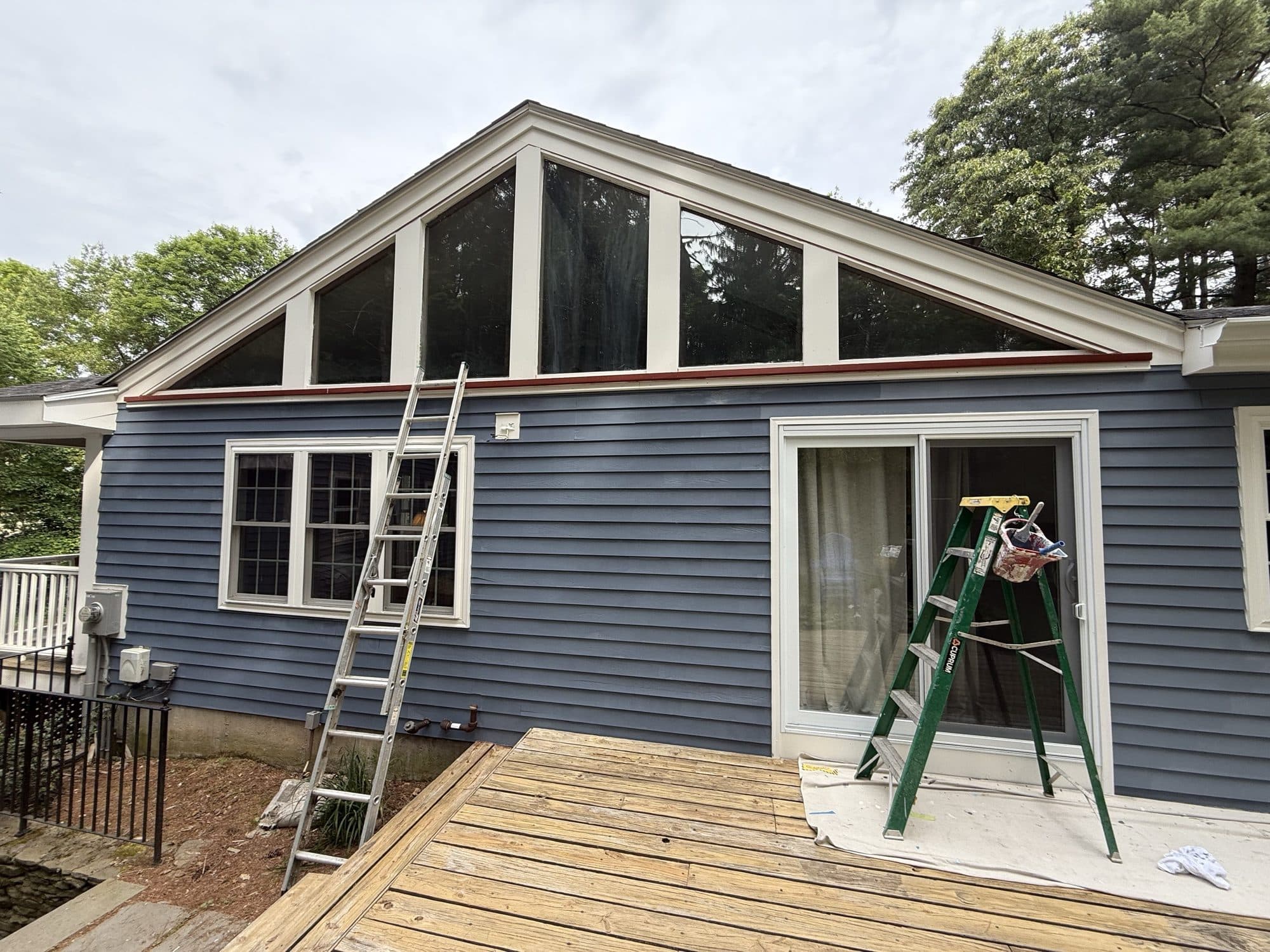 Blue clapboard home mid-project with ladders on site