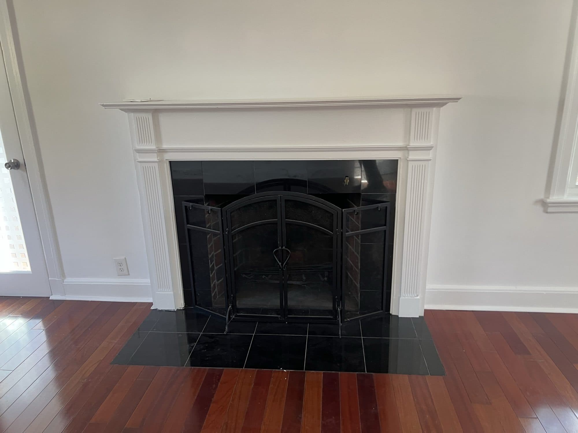 Fireplace with a hand-finished white mantel on cherry floors