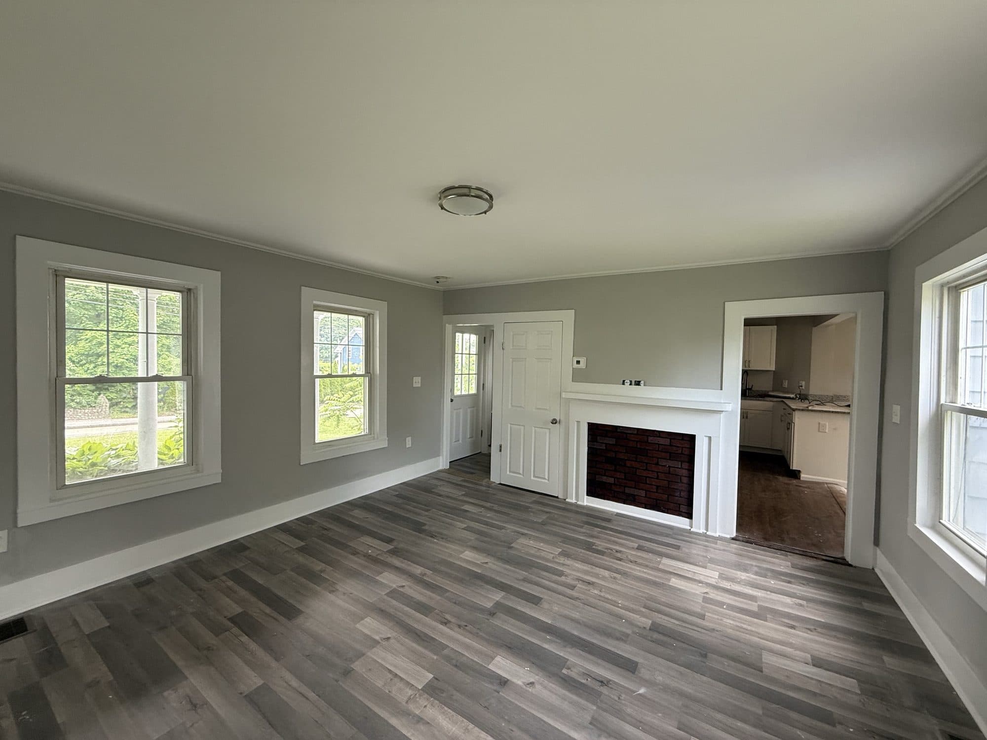 Living room with grey plank flooring and a white fireplace